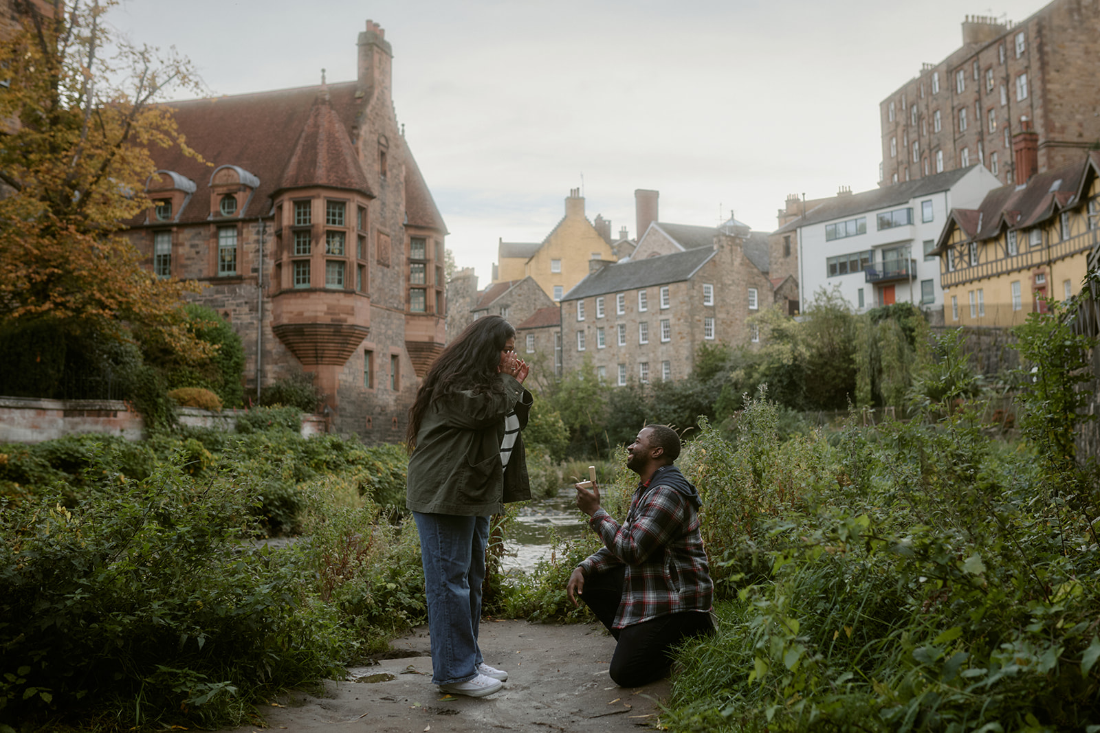 Emotional proposal in Dean Village, Edinburgh with man on one knee beside the river path