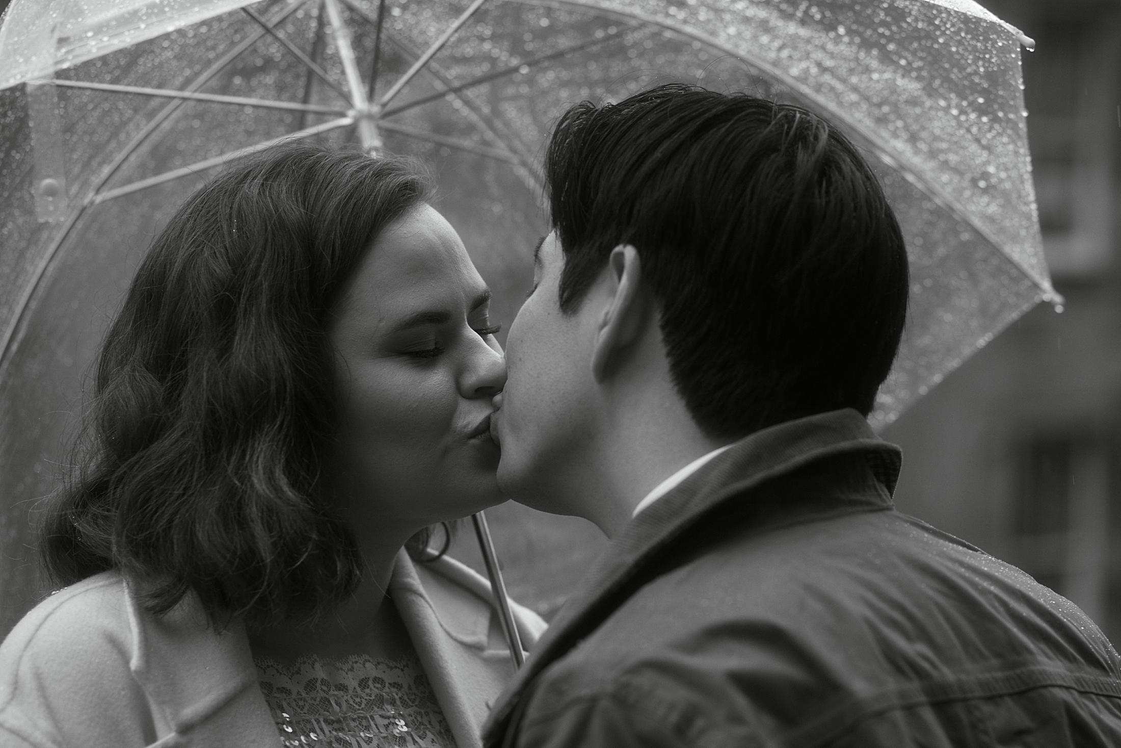 Couple kissing under umbrella in rain during Edinburgh Old Town elopement