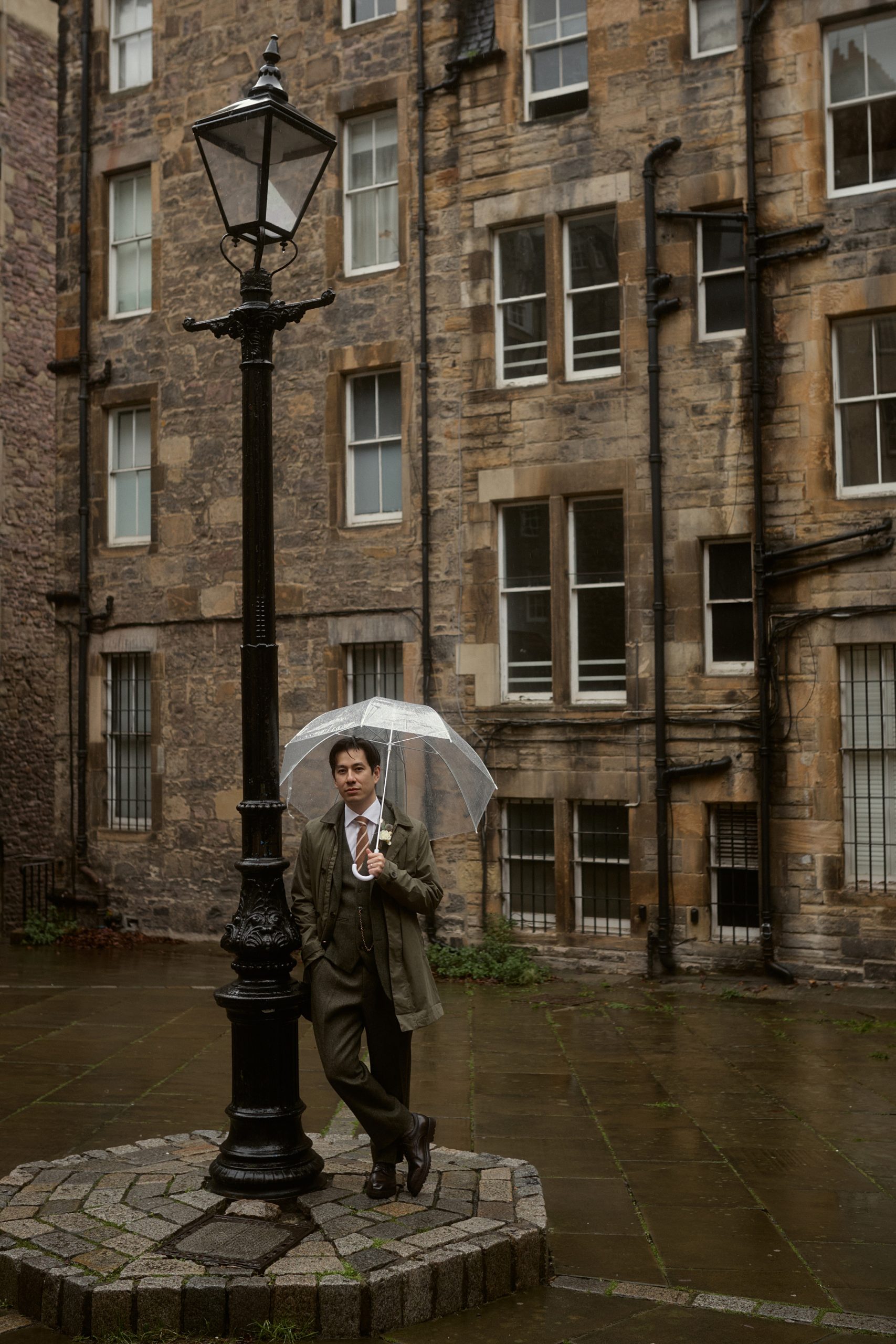Groom under umbrella at Writers’ Museum courtyard in Edinburgh Old Town after elopement ceremony