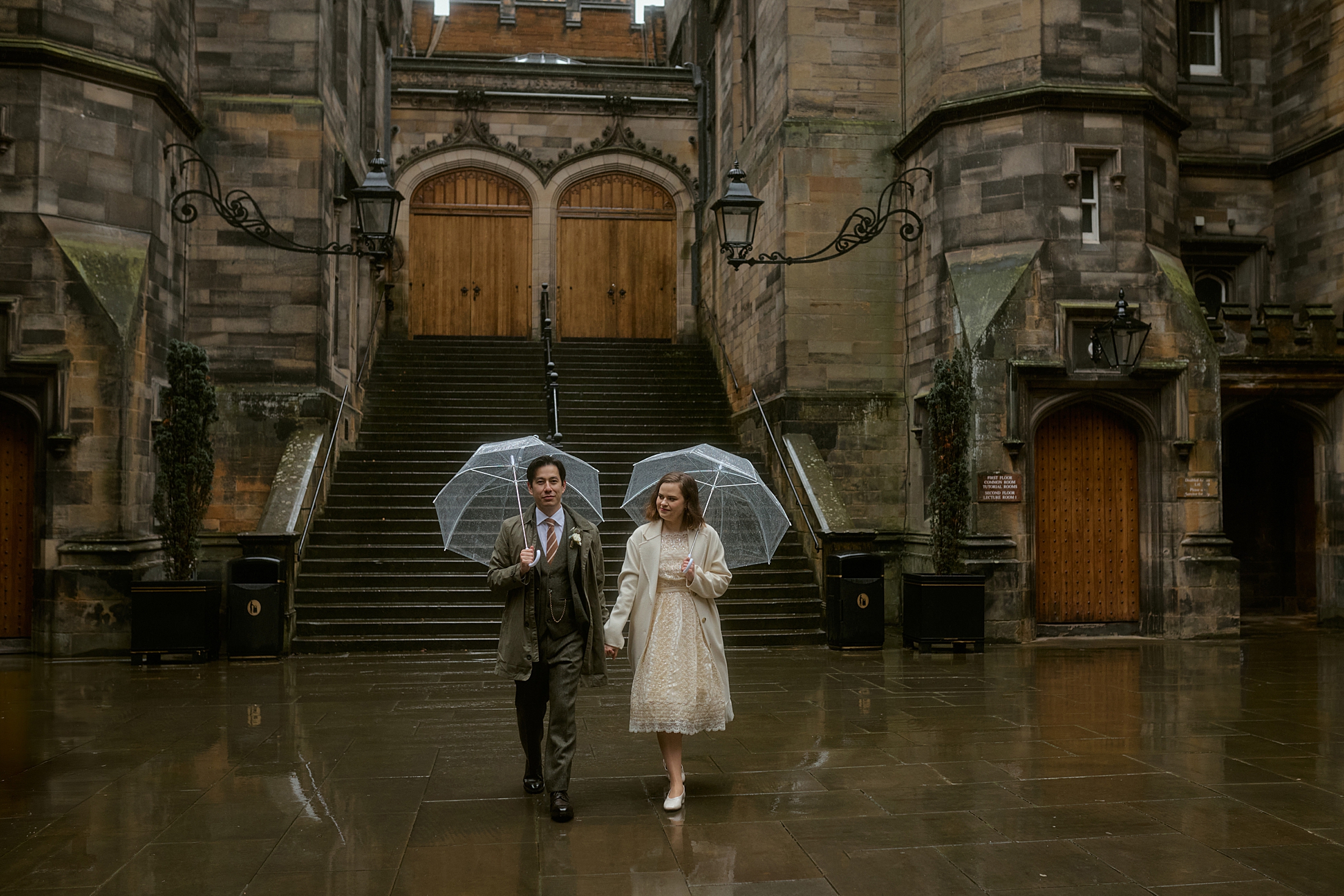 Couple walking in the rain at New College courtyard during Edinburgh elopement