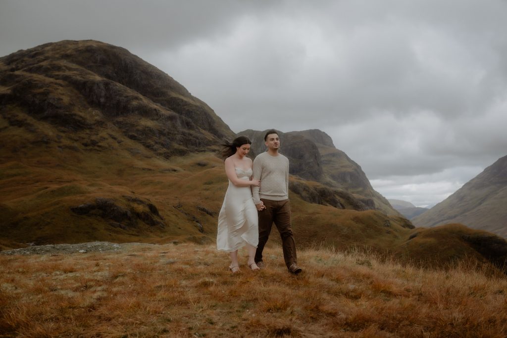 Couple walking through Glencoe before a surprise proposal in Scotland