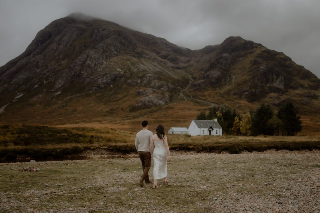 Couple walking in Glencoe with mountain views after a surprise proposal