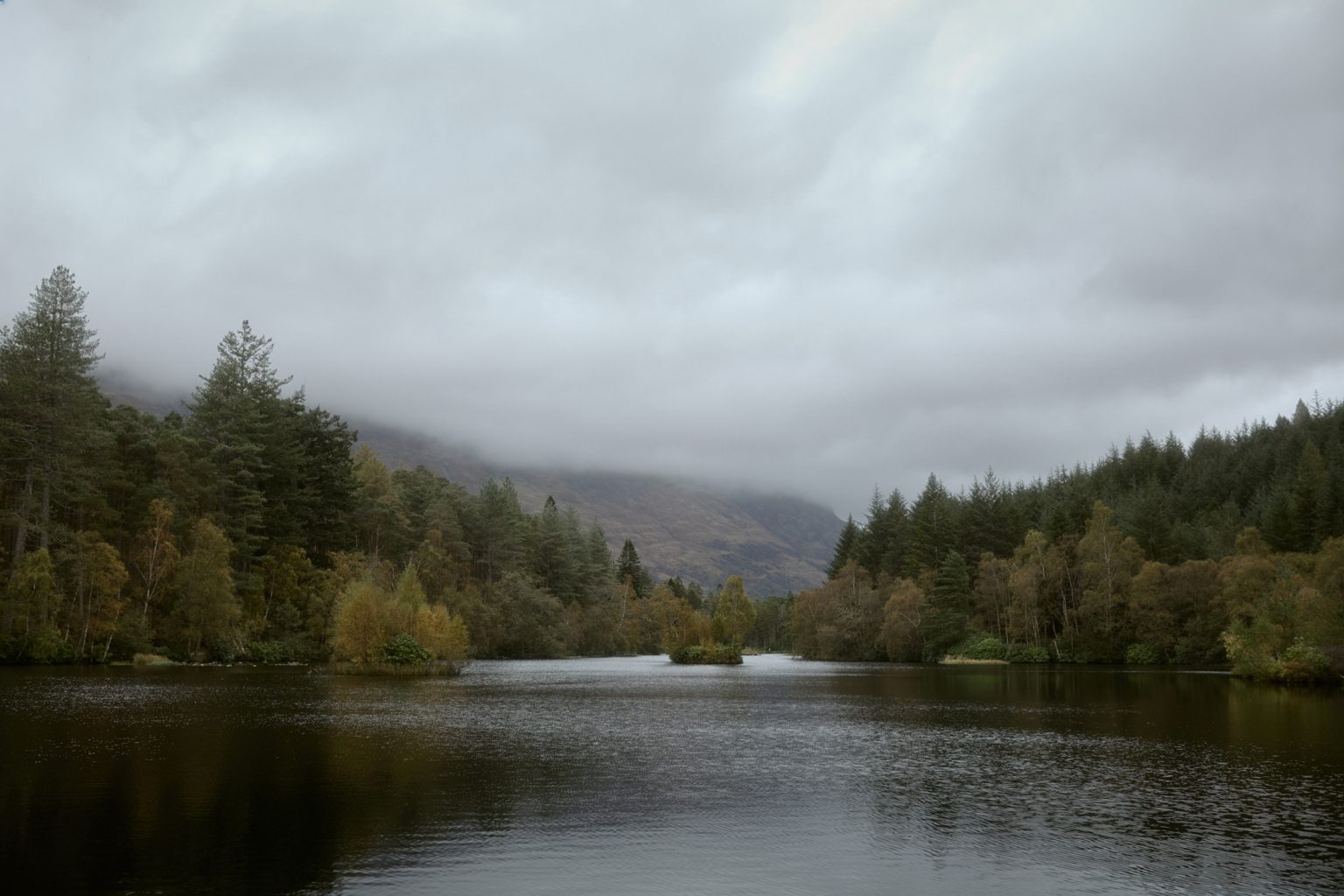 Glencoe Lochan landscape with autumn trees and misty mountains in the Scottish Highlands