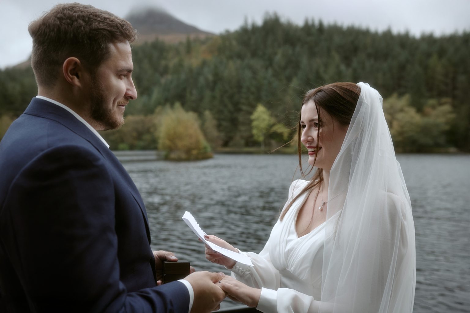 Couple exchanging vows during Glencoe Lochan elopement by the water in autumn