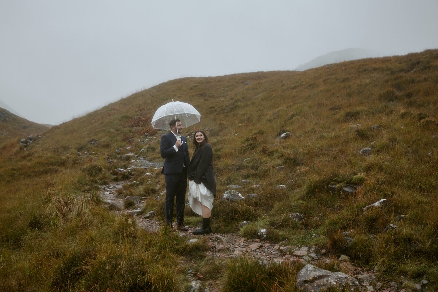 Couple walking in rain during private vow exchange in Glencoe Scottish Highlands